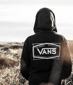 Home A man stands alone wearing a hoodie in an open field, embodying solitude and serenity outdoors.